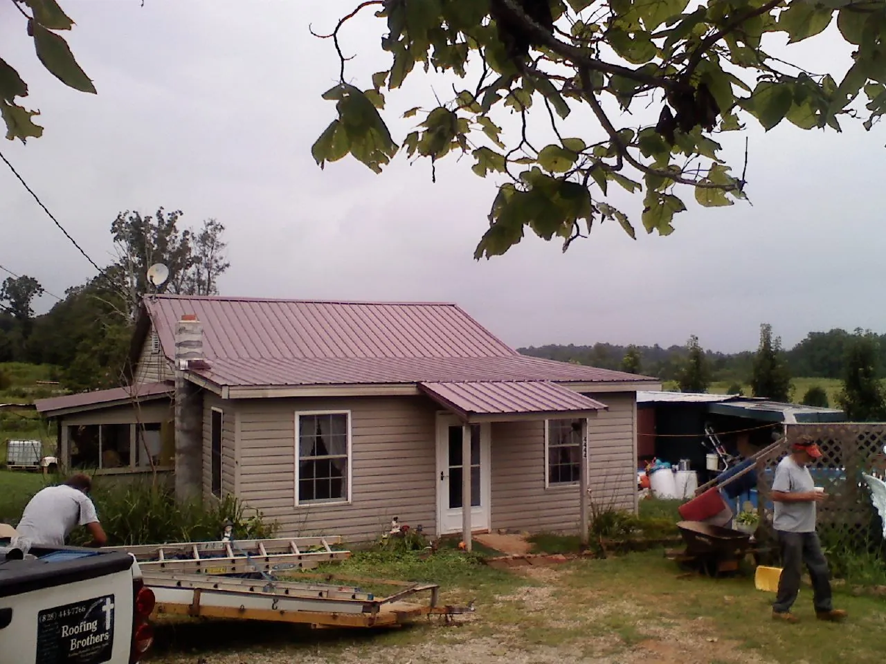 Crew finishing a mauve metal roof on a small farmhouse in Alpine
